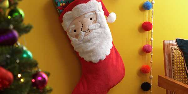 A Santa themed Christmas stocking with a yellow background. 